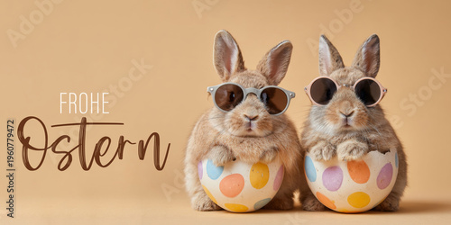 Frohe Ostern Konzept, Ferien Feiertag Grußkarte, Karte mit deutschem Text - Zwei lustige Osterhasen mit sonnenbrille und Osterei isoliert auf beigem Hintergrund