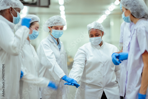 Cuadro en lienzo Team of food factory workers coordinate tasks and confirm workflow before starting production