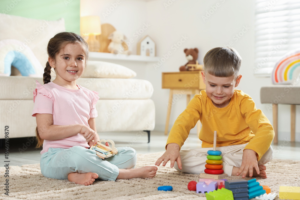 Naklejka premium Cute little friends playing with educational toys on floor at home