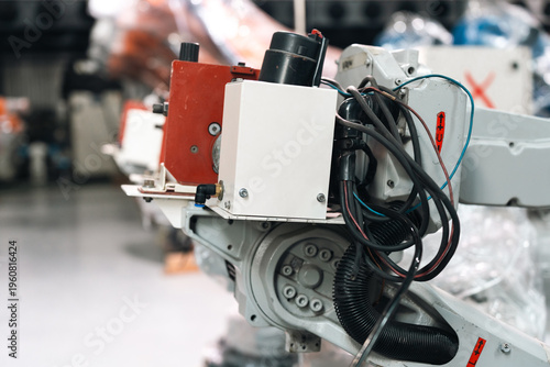 Industrial robot arm auto welding equipment in factory, metal gear joint with cable wiring and control box focus detail, modern manufacturing technology atmosphere