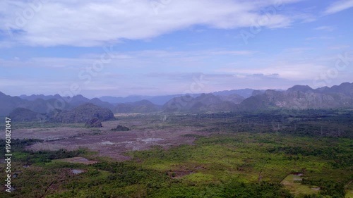 Very high altitude circling aerial view of tropical mountainous landscape, with power cables running through the landscape.