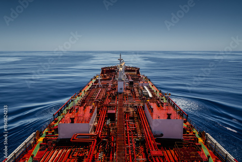 High angle view of a large oil tanker vessel deck with red pipes sailing in the deep blue calm ocean