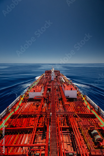High angle view of a large oil tanker vessel deck with red pipes sailing in the deep blue calm ocean