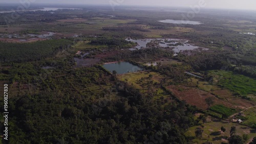 Airborne aerial view of agricultural landscape with farmlands,fields, lakes and dense vegetation.