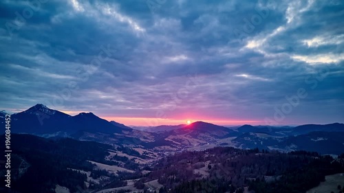 Aerial hyperlapse of sunset over mountain valley with dramatic clouds