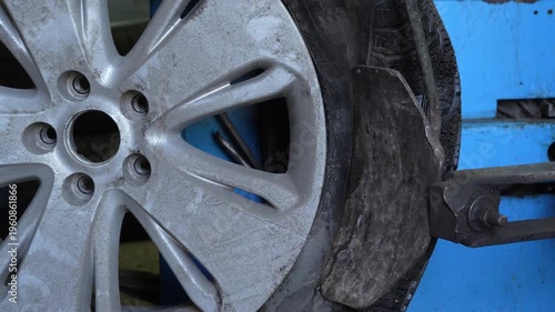 Close up of car wheel during tire removal using tire changing machine in auto repair workshop. Automotive service, maintenance and repair concept. 4K video.