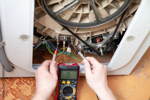 Checking the heater in a washing machine with a multimeter on the floor