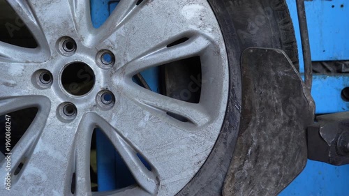 Mechanic rotates car wheel and positions tire changing tool on machine in auto repair shop. Automotive service, maintenance and tire replacement process. 4K video.