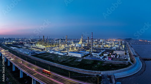 Quadro em tela Aerial view of large petrochemical refinery and industrial park with highway traffic at dusk, illustrating energy infrastructure and manufacturing power