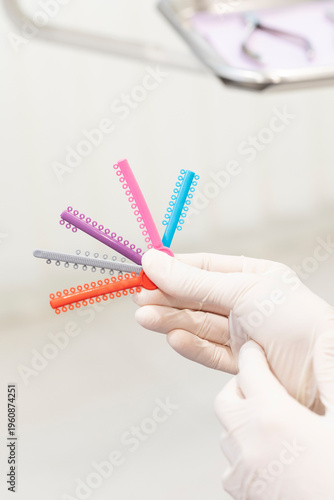Obraz na plátně Dentist hand holding colorful orthodontic elastic ligatures