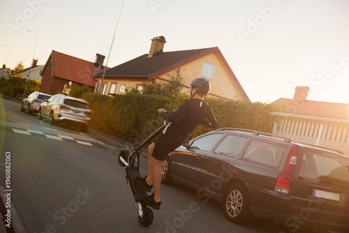 Full length of boy performing stunts on electric scooter on road