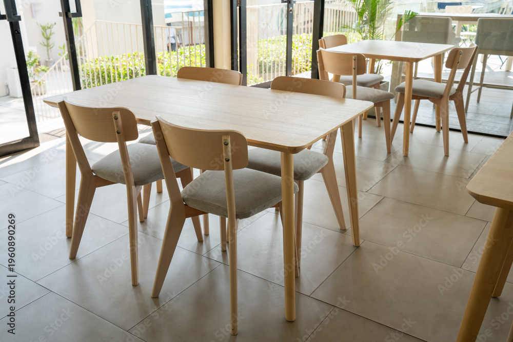 Fototapeta premium Modern minimalist cafe interior with wooden tables and chairs. Bright airy restaurant dining area with Scandinavian furniture design overlooking the sea. Ideal for lifestyle and decor.