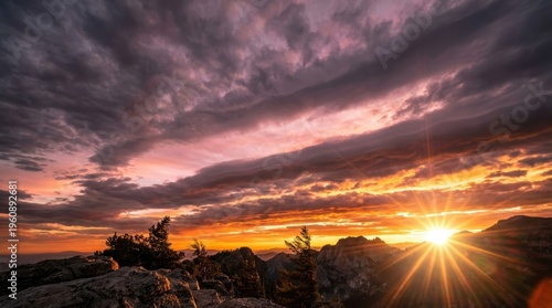 Breathtaking Sunset Over Mountain Peaks with Dramatic Clouds and Radiant Sunburst in Nature