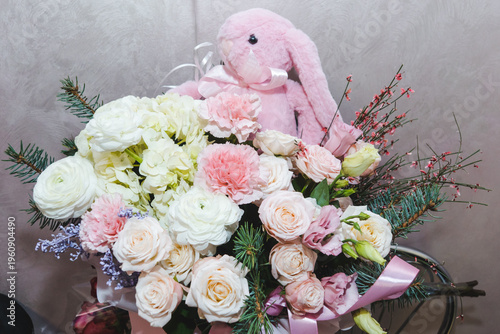 Romantic gift. A bouquet of flowers decorated with spruce branches and a pink plush rabbit. A flower arrangement of roses, carnations and hydrangeas and a cute soft toy.