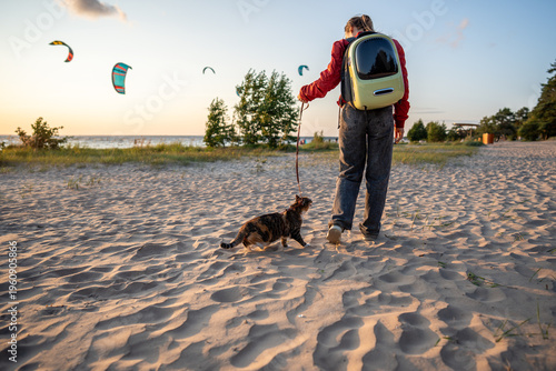 Foto Adventurous cat walking on leash with owner along sandy beach
