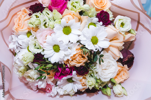 Mixed bouquet of various types of flowers and colors. Delicate pastel, red and pink roses, white chrysanthemums decorated with green leaves. Floristry and floral design concept.