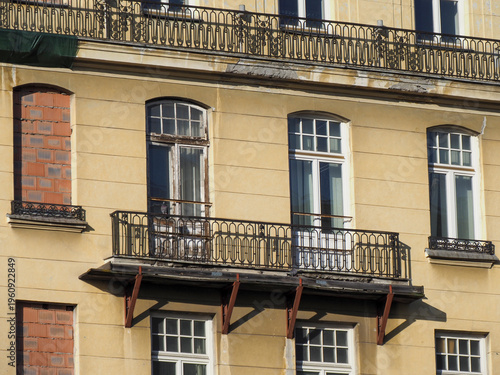 Detailed view of windows and ornate balconies on a historic yellow facade
