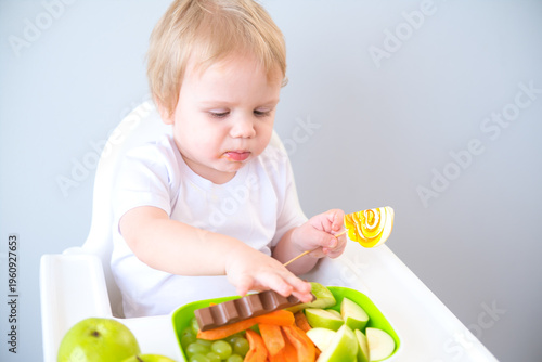 cute baby eating sweets sitting in a baby chair. weaning