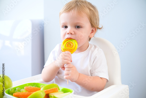 cute baby eating lollipop sitting in a baby chair. weaning