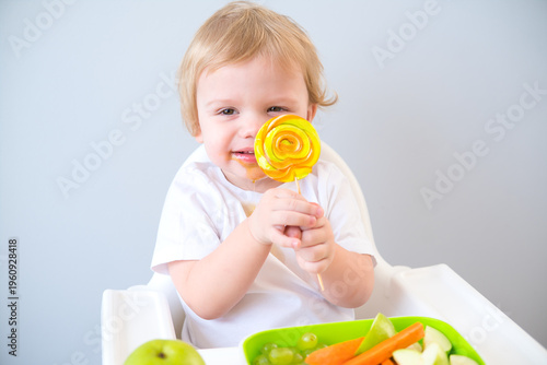 cute baby eating lollipop sitting in a baby chair. weaning
