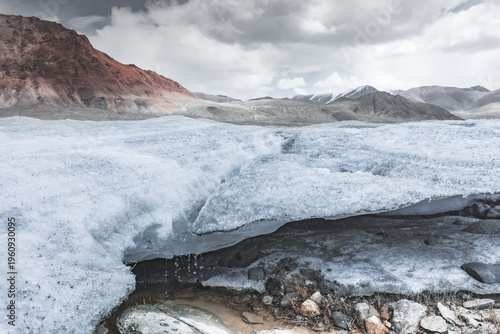 Disintegration of the snow layer in the mountains by a river and stream, water flowing and snow melting in the highlands of the Tien Shan in the Pamirs of Tajikistan