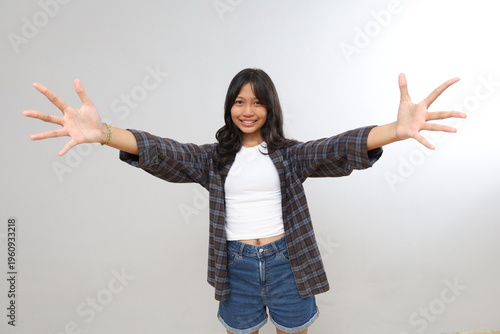 Fotografie Beautiful smiling teenage girl giving a hug, stretching her arms forward to be hugged, asking for a caress, wanting to hold something, standing isolated on a gray background
