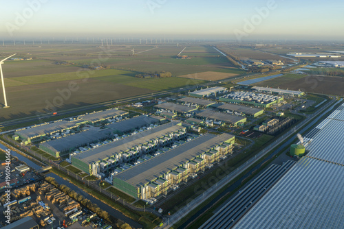 Aerial view of modern data center complex processing vast amounts of information, integrating technology with renewable wind energy in an agricultural area, Middenmeer, Netherlands.