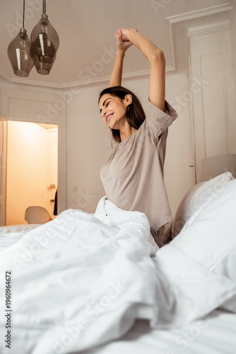 Happy woman stretching in bed after waking up, morning routine and healthy lifestyle