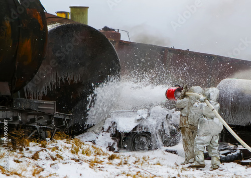 Photos Firefighters spray foam on a large tank after a train derailment in snowy condit