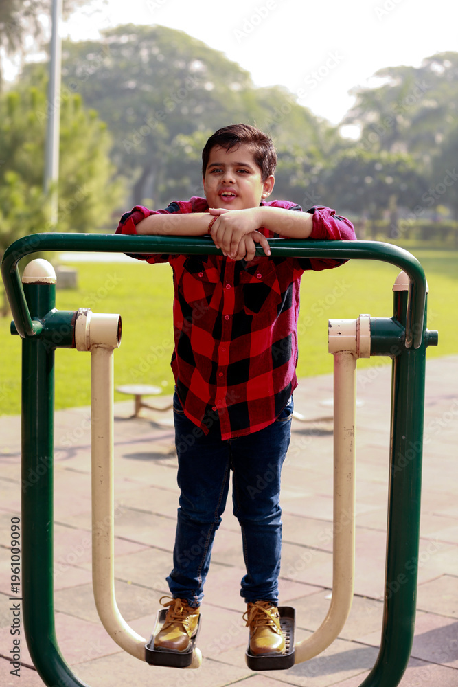 Fototapeta premium Elementary child exercising on single surfer pendel machine outdoor in nature.
