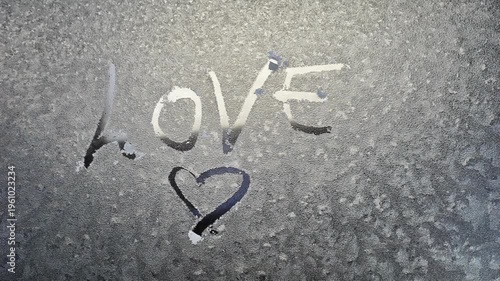 handwritten text love and heart shape on frosty car window melting