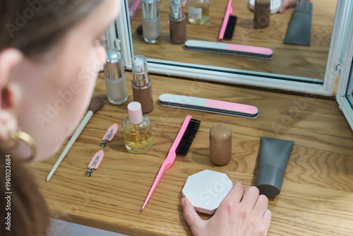 Φωτογραφία Teenage girl with OCD, carefully arranging make up items on dressing table in be