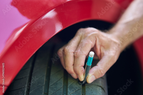 Foto Close up of man using  gauge to check tyre tread depth on car