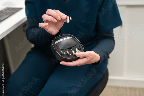 Close up of female audiologist demonstrating different models of hearing aid at audiology clinic