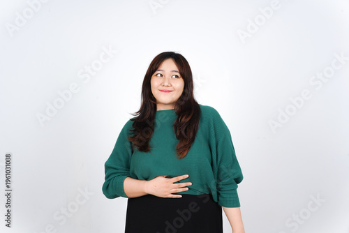 Asian woman smiling and looking sideways while holding her stomach