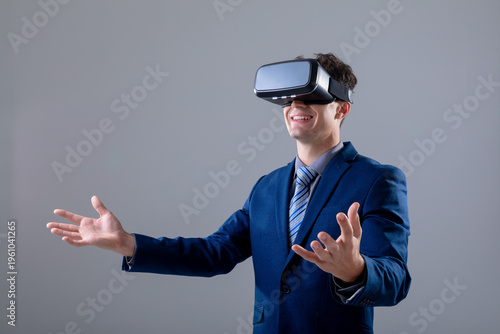 Caucasian businessman wearing vr headset widening his arms, isolated on grey background