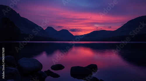 Majestic sunset over serene lake reflecting vibrant hues of purple and pink. Scenic mountains create a peaceful backdrop.
