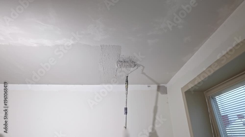 Close up view of smooth ceiling plaster application with roller creating even texture during renovation. Sweden.
