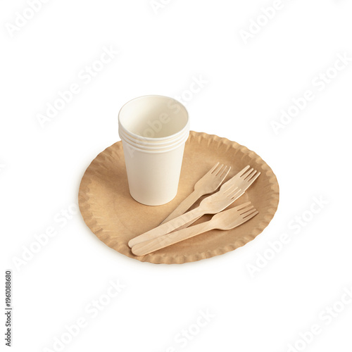 Brown kraft paper plate, paper cups and wooden forks. Disposable tableware set isolated on white background. Eco-friendly cookware for piknik, close-up.