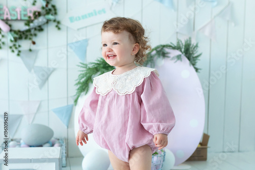 Wallpaper Mural Adorable smile little toddler girl with curly hair in a pink dress near Easter interior room. Cute child surrounded by bunny decorations, spring festive decor. Easter celebration concept, springtime Torontodigital.ca