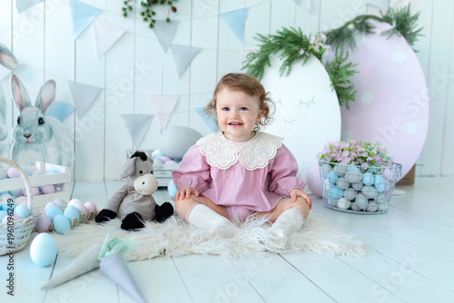 Wallpaper Mural Adorable toddler girl in Easter-themed room with decorative eggs, bunny toys, and spring decorations. Cute child wearing a pink dress with lace collar, smiling gently. spring holiday atmosphere Torontodigital.ca