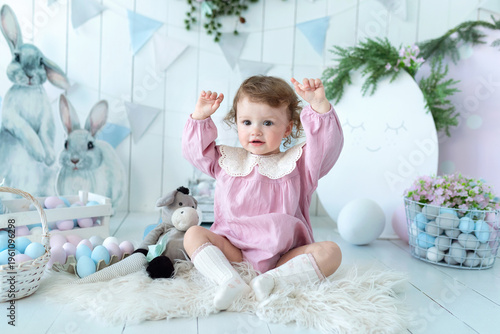 Wallpaper Mural Adorable baby girl in Easter-themed room with decorative eggs, bunny toys, and spring decorations. Cute child wearing a pink dress with lace collar, smiling gently. spring holiday atmosphere Torontodigital.ca