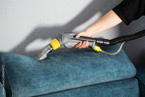 Deep cleaning upholstery with a steam cleaner on a blue sofa for a fresh living room appearance