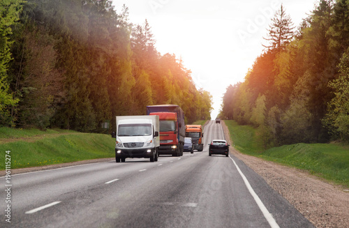 Fotografie Cargo transportation on country road with multiple vehicles and semi-trailer tru