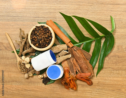 Flat lay of traditional Thai herbs and aromatic ingredients used in herbal inhaler and natural remedies on wood.