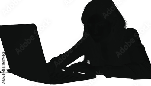 Dark figure typing intently on a laptop computer showing intense focus and digital work.