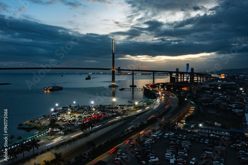 Aerial view of a long bridge extending across the water, connecting to the city's skyline, with light trails weaving through the roads below, Cebu City, Central Visayas, Philippines.