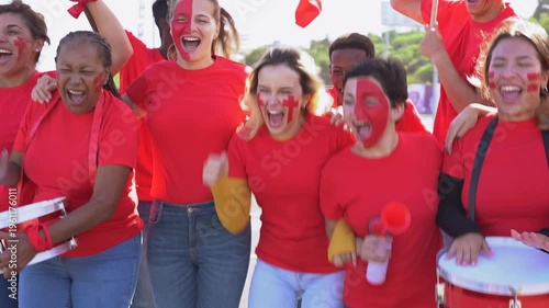 Multi generational sport fans people having fun screaming outside of stadium - Group of red football supporters celebrating goal outdoor 