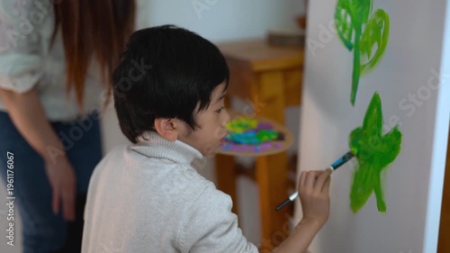 Little asian boy painting on canvas at home - Childhood, nanny, daycare and creative art work concept