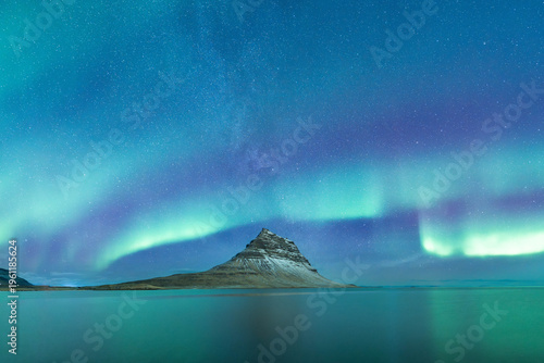 Kirkjufell mountain with northern lights and the milky way behind it. Kirkjufell mountain on the Snæfellsnes peninsula in Iceland.